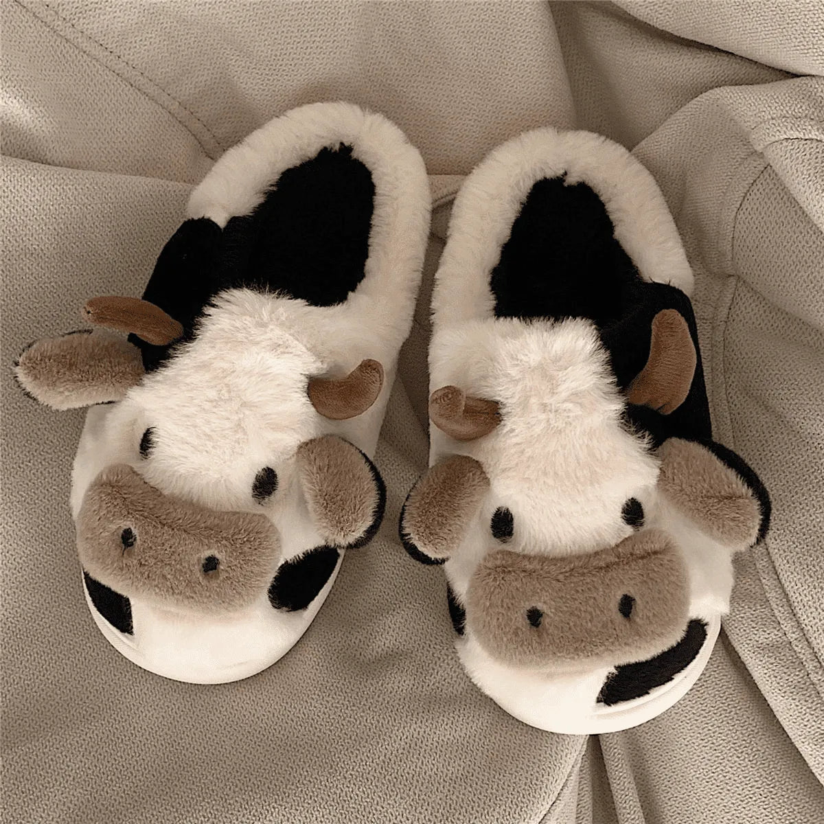 Image Chaussons Vache Mignonne posés sur un canapé